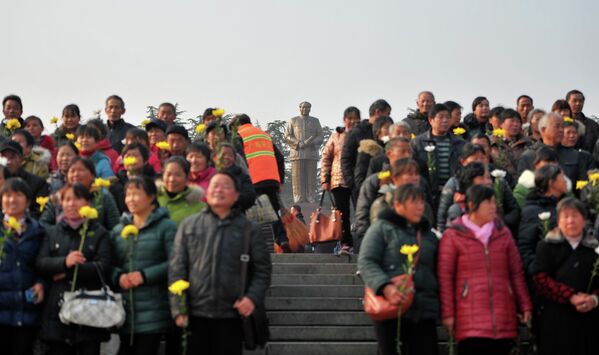Люди с цветами перед статуей Мао Цзэдуна