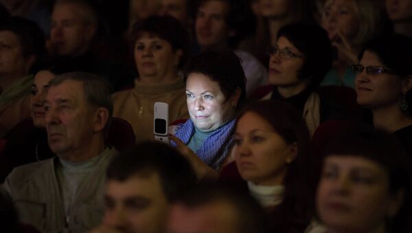 Женщина с мобильным телефоном в зрительном зале. Архивное фото