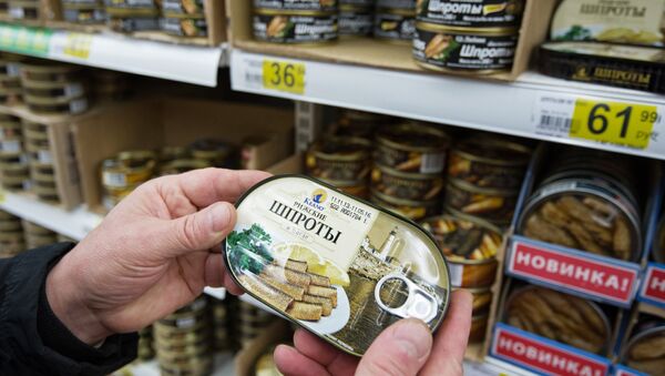 Покупатель выбирает рыбные консервы шпроты в одном из московских супермаркетов