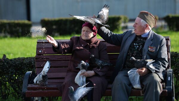 Пожилые люди кормят голубей