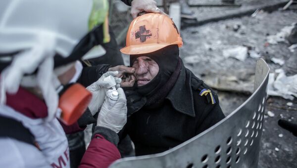 Протестующие оказывают медицинскую помощь мужчине, пострадавшему во время столкновений с сотрудниками правоохранительных органов у стадиона Динамо в Киеве. Архивное фото