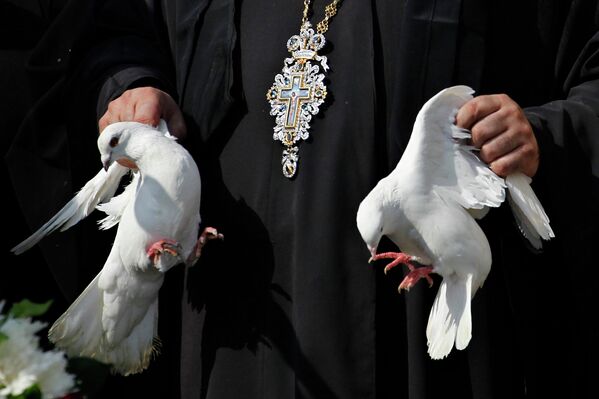Христианский священник держит голубей во время мессы