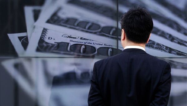 Бизнесмен смотрит на экран с изображением 100-долларовых банкнот. Архивное фото