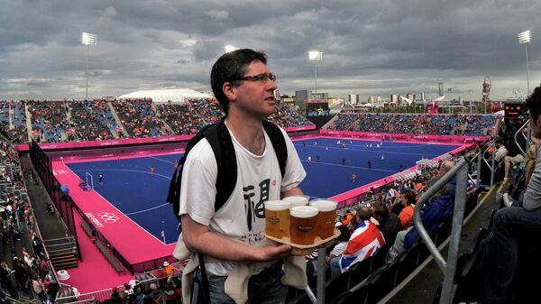 Болельщик несет пиво на трибуне стадиона перед игрой 