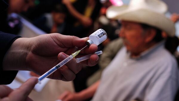 Медсестра делает прививку от гриппа в Мехико. Фото с места событий