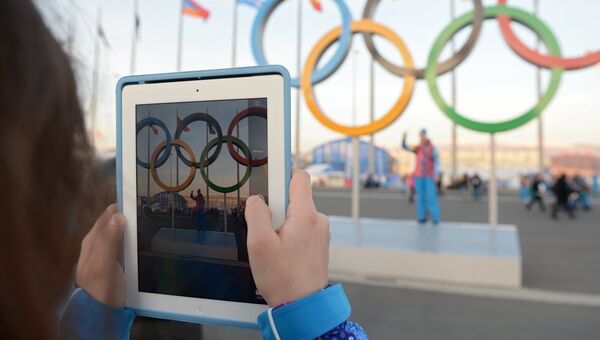 Волонтеры фотографируются у Олимпийских колец перед началом церемонии открытия XXII зимних Олимпийских игр в Сочи.