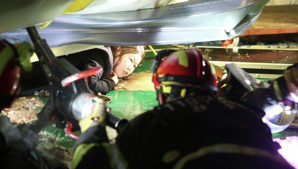 Спасатель пытается помочь студентке, оказавшемуся под завалами в результате обрушения здания в курортном городе Кенджу в Южной Корее