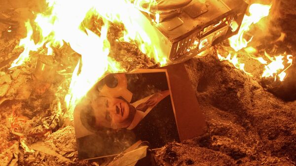 Портрет украинского президента Виктора Януковича горит возле разрушенного здания службы безопасности во Львове