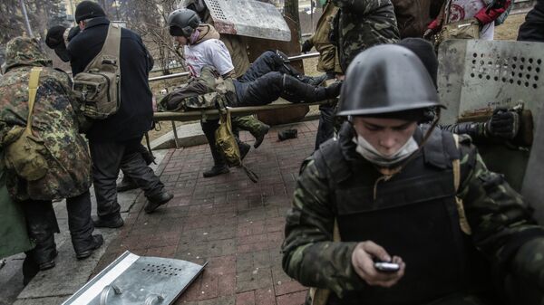 Сторонники оппозиции несут раненного во время столкновений с сотрудниками правопорядка в Киеве. Архивное фото