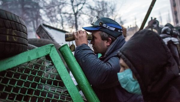 Сторонник оппозиции наблюдает в бинокль за милицией с баррикады, архивное фото
