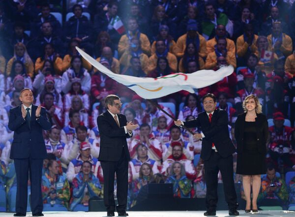 Президент Международного олимпийского комитета Томас Бах (второй слева) передает Олимпийский флаг мэру города Пхенчхана Ли Сок Рэ