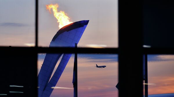 Самолет заходит на посадку на фоне чаши Олимпийского огня