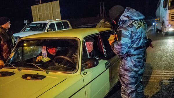 Сотрудник подразделения милиции специального назначения Беркут проверяет документы у водителя автомобиля на блокопосту на въезде в Крым в районе Армянска. Архивное фото