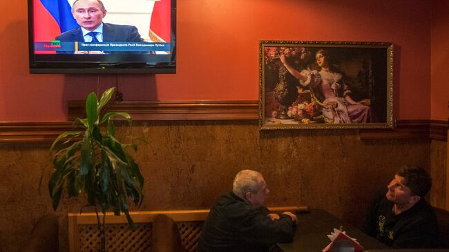 Жители Киева во время просмотра ТВ трансляции пресс-конференции президента России Владимира Путина