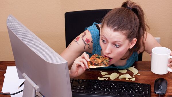 Девушка ест за компьютером, архивное фото