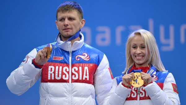 Ведущий Алексей Иванов и Михалина Лысова (Россия), завоевавшие золотые медали в спринтерской гонке в классе B 1-3 (слабовидящие) среди женщин в соревнованиях по лыжным гонкам