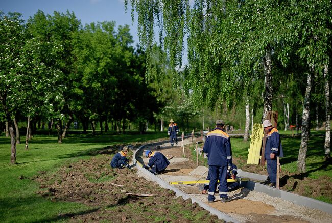 Рабочие возводят пешеходную дорожку в парке