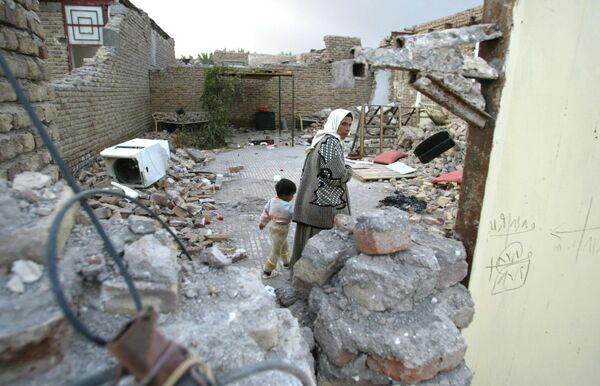 Иранская женщина с сыном ходит по руинам своего дома после землетрясения в Баме, Иран.