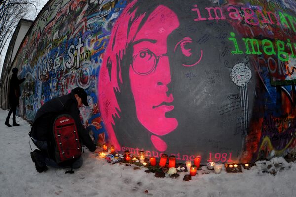 Мужчина зажигает свечу у Стены Леннона в Праге