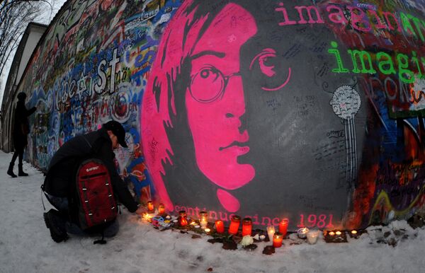 Мужчина зажигает свечу у Стены Леннона в Праге