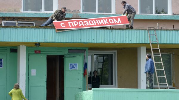 Демонтаж плаката С праздником на Доме культуры в поселке Ключи Камчатского края.