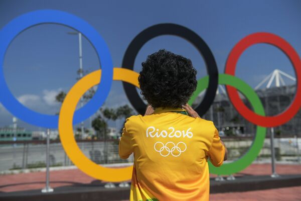 Мужчина у олимпийских колец в олимпийском парке в Рио-де-Жанейро