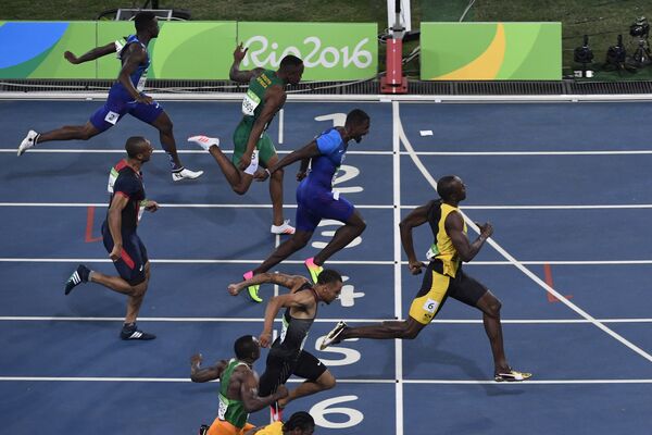 Ямайский спринтер Усэйн Болт (справа) финиширует первым в финальном забеге на 100 метров на Олимпийских играх 2016 года в Рио