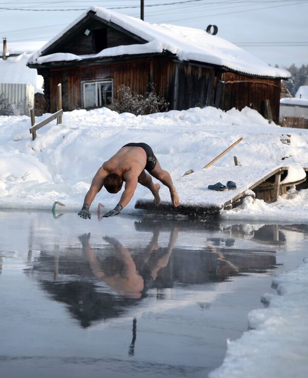 Любитель зимнего плавания из клуба моржей Белый Медведь купается в проруби на пруду в Екатеринбурге