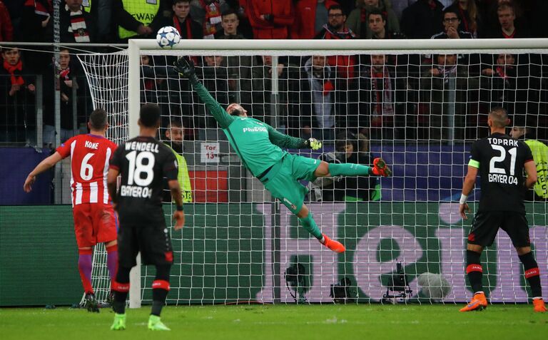 Голкипер Атлетико Анхель Мойя (в центре) отбивает мяч после удара футболиста Байера