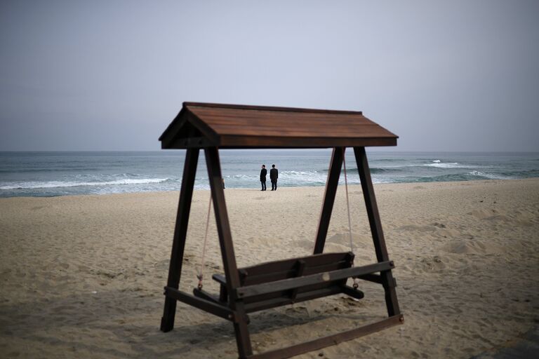 Мужчины в деловых костюмах на пляже Gyeongpo Beach в городе Каннын, Республика Корея