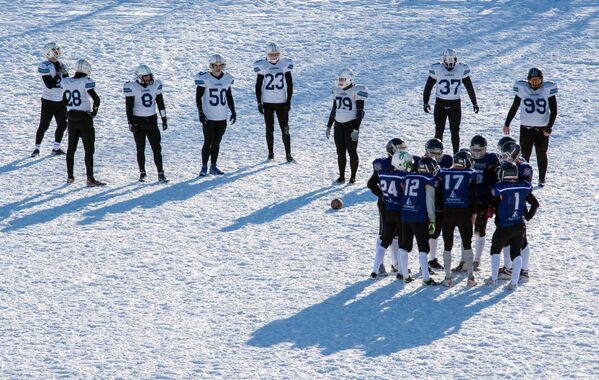 Игроки команды Айсберги (на втором плане) и игроки команды Оружейники в матче ежегодного турнира северных городов Snow Bowl 2017 по американскому футболу