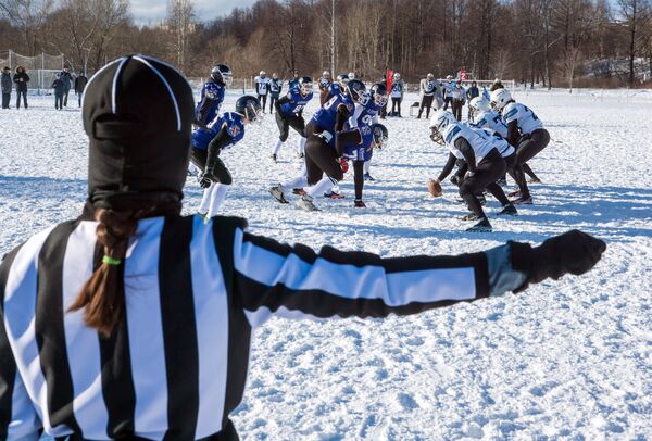 Игроки команды Айсберги (белая форма) и игроки команды Оружейники (синяя форма) в матче ежегодного турнира северных городов Snow Bowl 2017 по американскому футболу