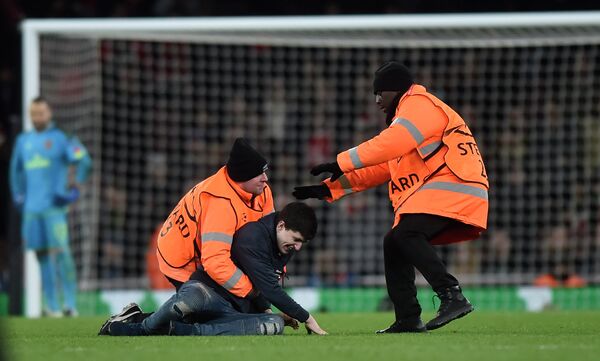 Стюарды задерживают болельщика, выбежавшего на поля во время матча Лиги чемпионов Арсенал - Бавария
