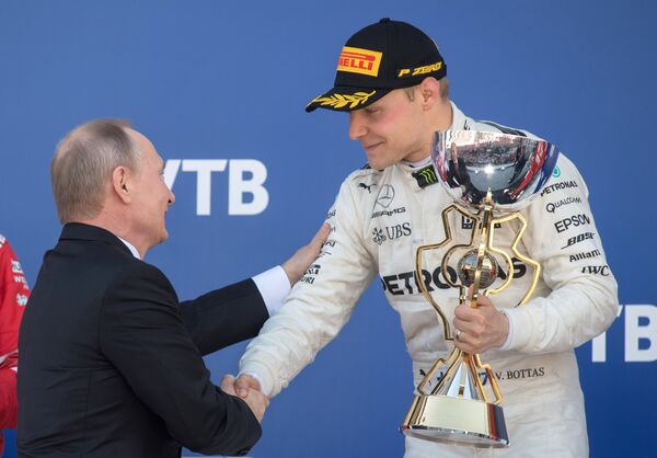 Президент РФ Владимир Путин награждает гонщика команды Мерседес Вальттери Боттаса (справа)