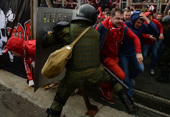 Сотрудник правоохранительных органов сдерживает болельщиков московского Спартака, прорывающихся на поле