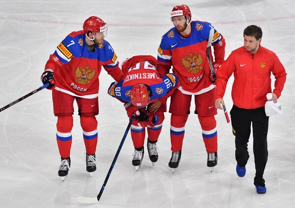 Хоккеисты сборной России Иван Телегин (слева) и Владислав Гавриков помогают Владиславу Наместникову покинуть лед