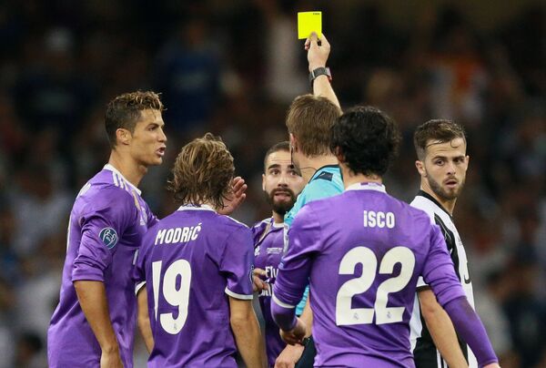 Главный судья матча Феликс Брих показывает жёлтую карточку защитнику Реала Даниэлю Карвахалю (третий слева)