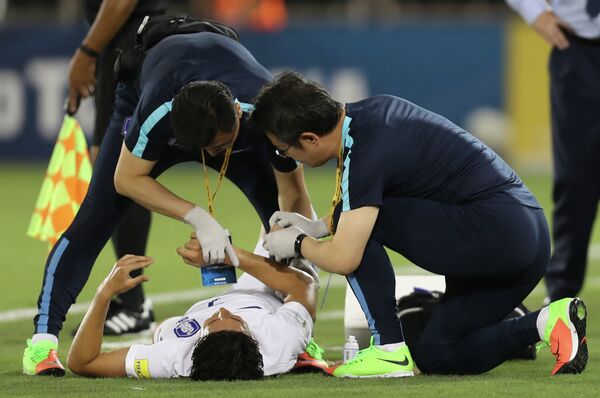 Медики оказывают помощь форварду сборной Кореи Сон Хын Мину