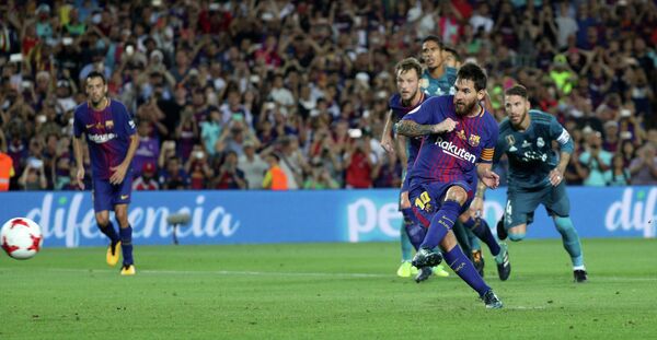 Форвард Барселоны Лионель Месси забивает мяч в ворота Реала