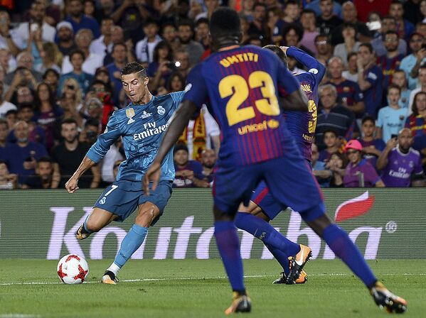 Форвард Реала Криштиану Роналду (слева) забивает мяч в ворота Барселоны