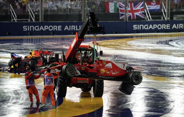 Работники автодрома на Гран-при Сингапура эвакуируют с трассы болиды гонщика Феррари Кими Райкконена (справа) и пилота Ред Булл Макса Ферстапенна