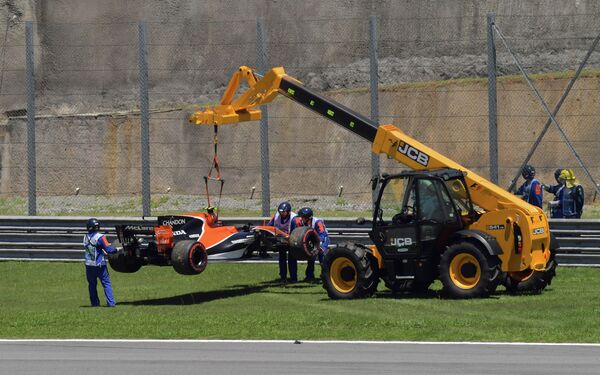 Сотрудники автодрома увозят болид пилота Макларена Стоффеля Вандорна во время этапа Гран-при Бразилии Формулы-1