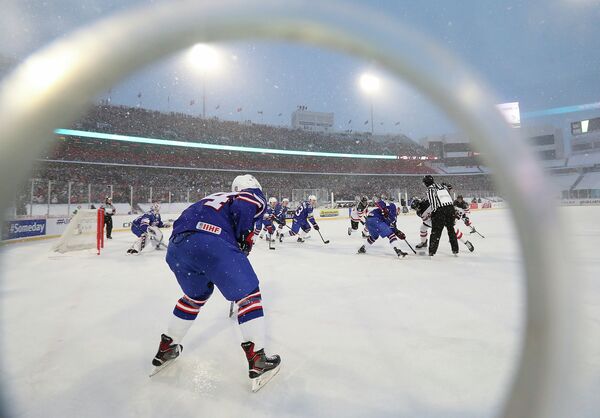 Игровой момент матча молодежного чемпионата мира по хоккею между командами США и Канады на открытом воздухе