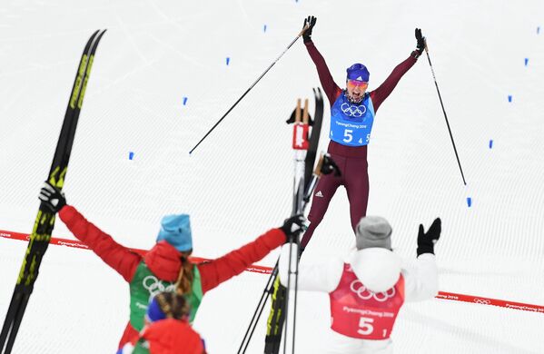 Российская лыжница Анна Нечаевская финиширует в олимпийской эстафете