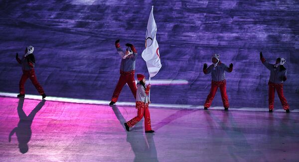 Волонтер несет олимпийский флаг, под которым на ОИ-2018 выступают атлеты из России
