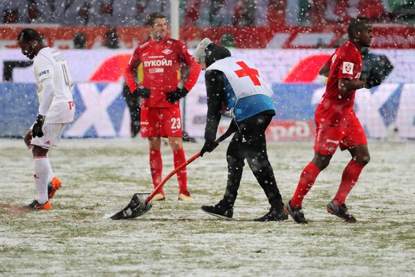 Расчистка от снега красной разметки на футбольном поле во время матча Локомотив - Спартак