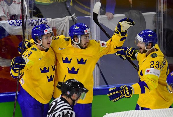 Хоккеисты сборной Швеции Маттиас Янмарк, Мика Зибанеджад и Оливер Экман-Ларссон (слева направо) радуются заброшенной шайбе