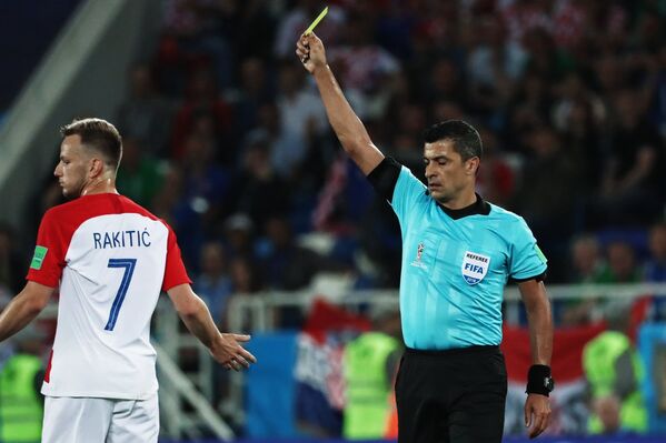 Главный судья Сандро Рикки (справа) показывает желтую карточку хорватскому полузащитнику Ивану Ракитичу