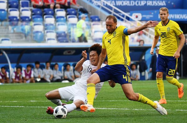 Защитник корейской сборной Ким Ён Гвон (Южная Корея) и шведский защитник Андреас Гранквист (Слева направо)