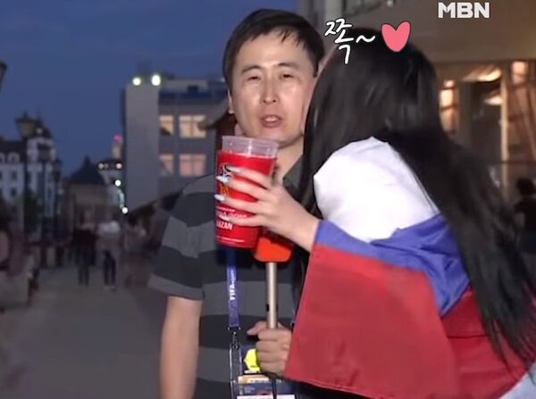 Болельщица целует корейского журналиста. Кадр из видео.